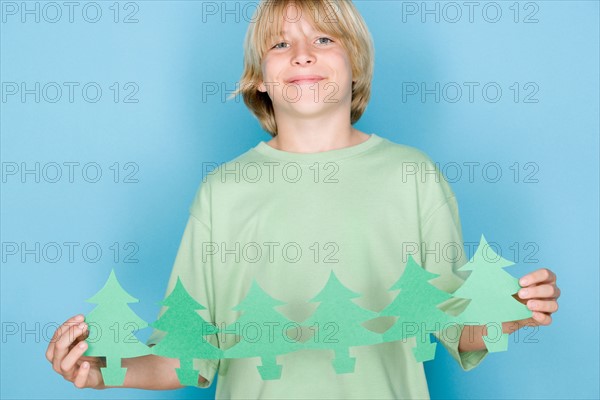 Studio shot portrait of teenage boy holding paper chain, waist up. Photo : Rob Lewine