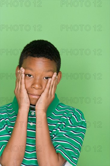 Studio shot portrait of young man with head in hands, head and shoulders. Photo : Rob Lewine