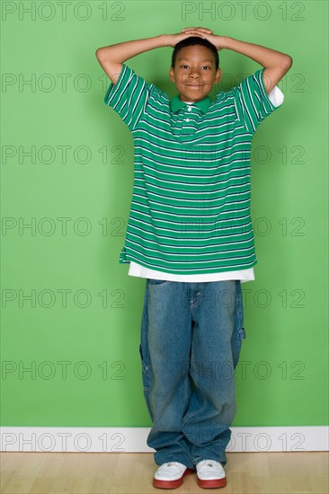 Studio shot portrait of young man with hands behind head, full length. Photo : Rob Lewine