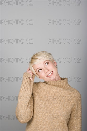 Studio shot portrait of young woman scratching head, waist up. Photo : Rob Lewine