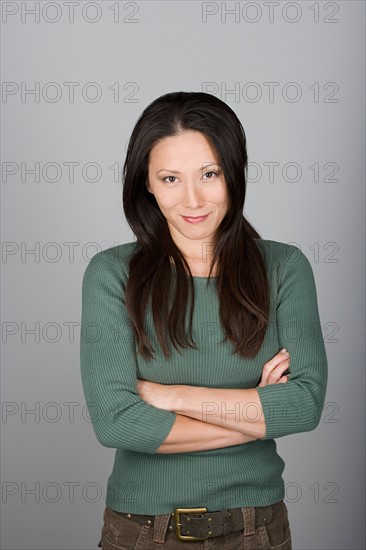 Studio shot portrait of mid adult woman with arms crossed, waist up. Photo : Rob Lewine