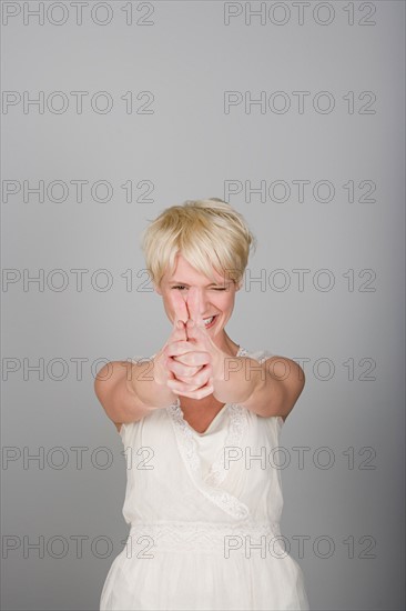 Studio shot portrait of mid adult woman aiming in viewer's side, waist up. Photo : Rob Lewine