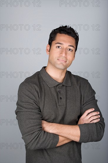 Studio shot portrait of mid adult man with arms crossed, waist up. Photo : Rob Lewine
