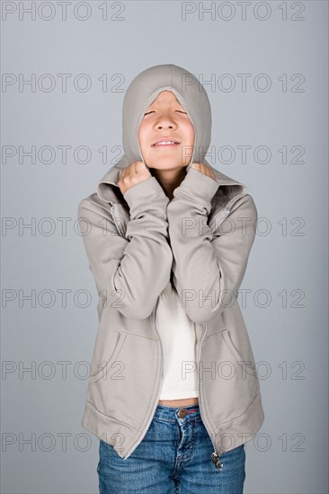 Studio shot portrait of teenage girl in hooded shirt, waist up. Photo : Rob Lewine