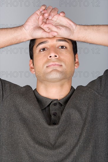 Studio shot portrait of mid adult man with arms raised, head and shoulders. Photo : Rob Lewine