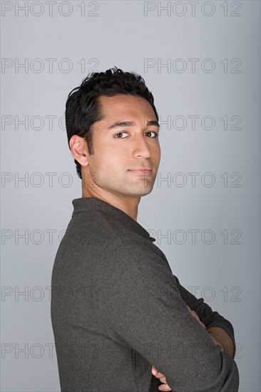 Studio shot portrait of mid adult man with arms crossed, head and shoulders. Photo : Rob Lewine