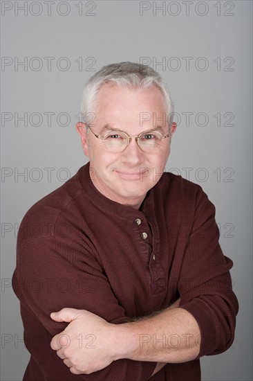 Studio shot portrait of senior man with arms crossed, head and shoulders. Photo : Rob Lewine