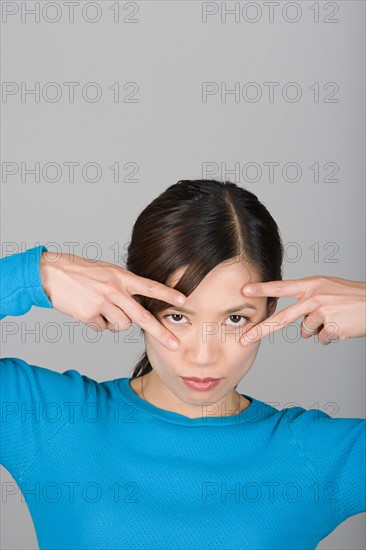 Studio shot portrait of mature woman with arms raised, head and shoulders. Photo : Rob Lewine