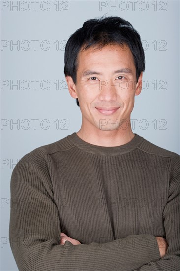 Studio shot portrait of mature man with arms crossed, head and shoulders. Photo : Rob Lewine