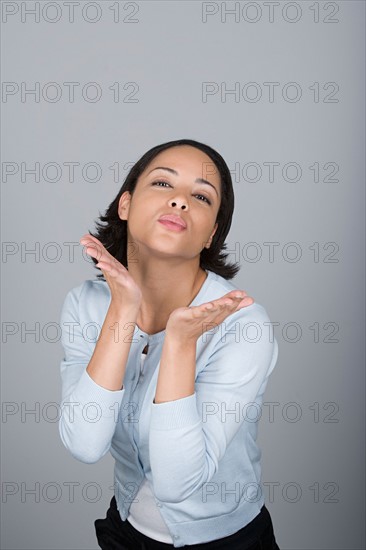 Studio portrait of attractive mid adult woman blowing kiss. Photo : Rob Lewine