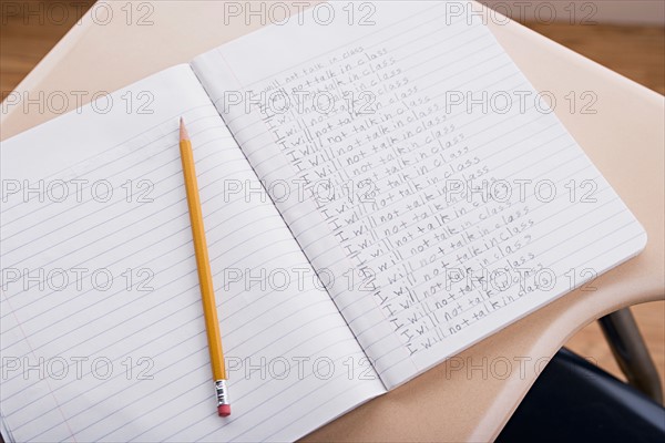 Copybook with website address written in it an pencil lying beside. Photo : Rob Lewine