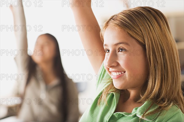 Schoolgirl rising hand in classroom. Photo : Rob Lewine