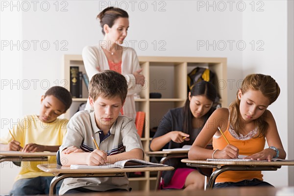 Female teacher is supervising as class is writing in their copybooks. Photo : Rob Lewine