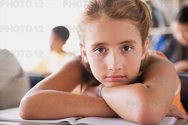 Bored schoolgirl leaning on desk. Photo : Rob Lewine