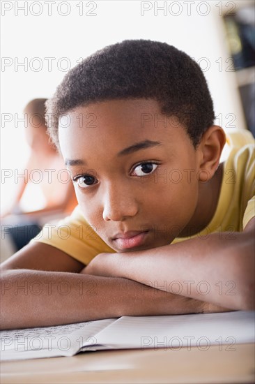 Bored schoolboy leaning on desk. Photo : Rob Lewine