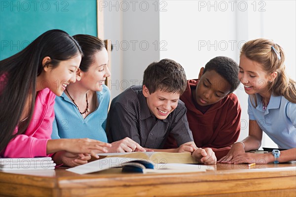 Group of school children having fun while reading book. Photo : Rob Lewine