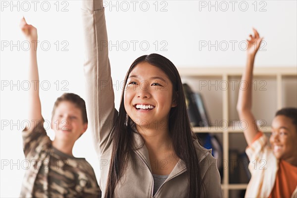 School children rising hands in classroom . Photo : Rob Lewine