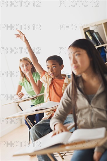 School children rising hands in classroom . Photo : Rob Lewine