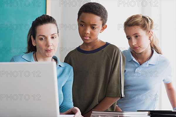 Boy and girl with teacher using laptop . Photo : Rob Lewine