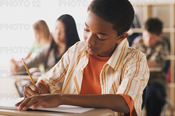 Boy doing notes in classroom. Photo : Rob Lewine