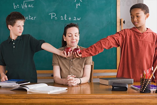 Two boys holding apples in front of teacher. Photo : Rob Lewine