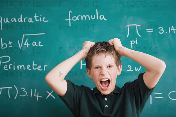 Frustrated schoolboy in front of blackboard. Photo : Rob Lewine