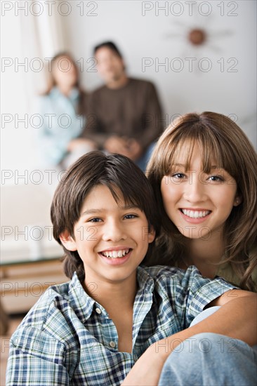 Portrait of brother and sister, parents in background. Photo : Rob Lewine