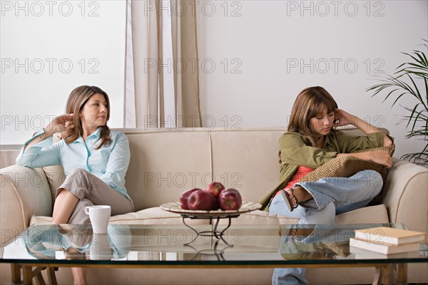 Angry daughter sitting with mother on sofa. Photo : Rob Lewine