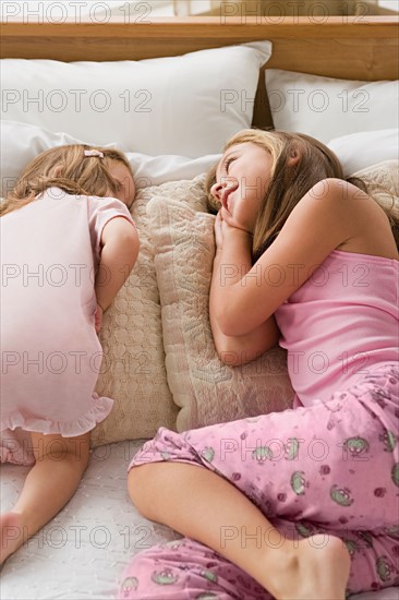 Sisters (8-9, 12-13) lying together on bed. Photo : Rob Lewine