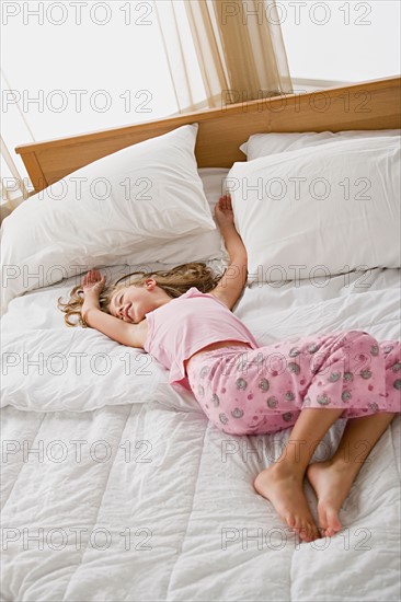 Girl lying in bed in playful pose. Photo : Rob Lewine