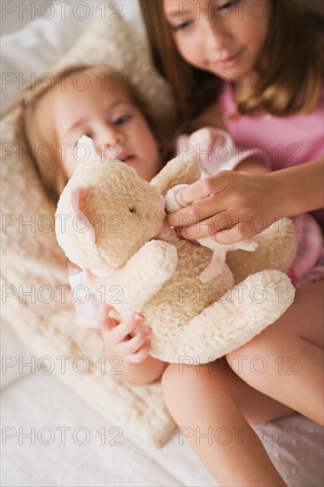 Two sisters playing with teddy bear. Photo : Rob Lewine
