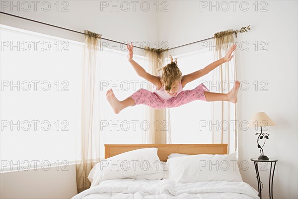 Girl (12-13) jumping on bed. Photo : Rob Lewine