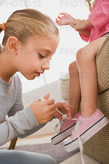 Girl (12-13) tying her younger sister's (8-9) shoes. Photo : Rob Lewine