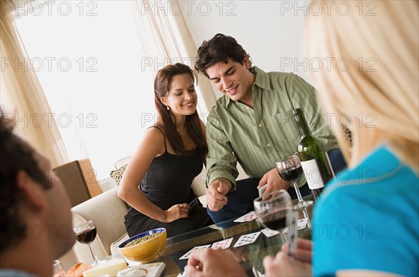 Couples on sofa at home party playing cards. Photo : Rob Lewine