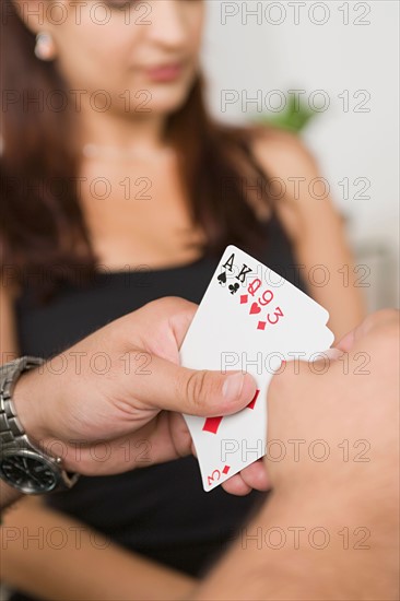 Man's hands holding cards. Photo : Rob Lewine
