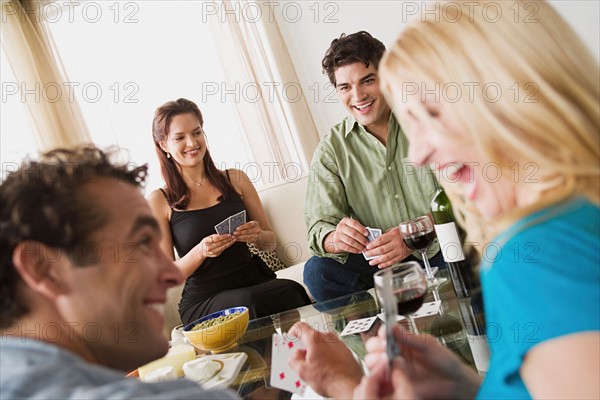 Couples on sofa at home party playing cards. Photo : Rob Lewine