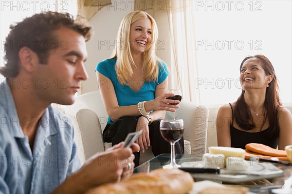 Smiling people at home party playing cards. Photo : Rob Lewine