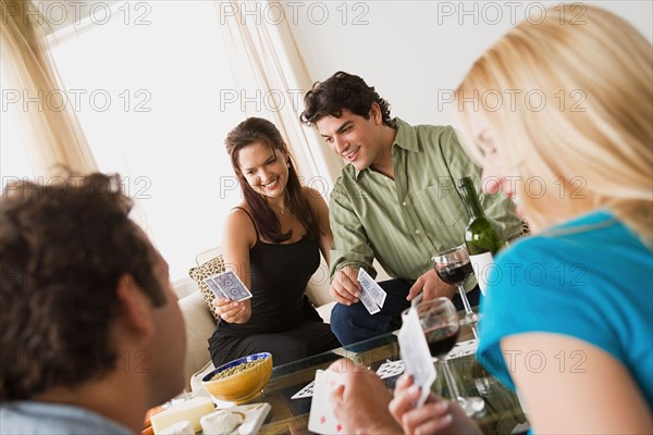 Couples on sofa at home party playing cards. Photo : Rob Lewine