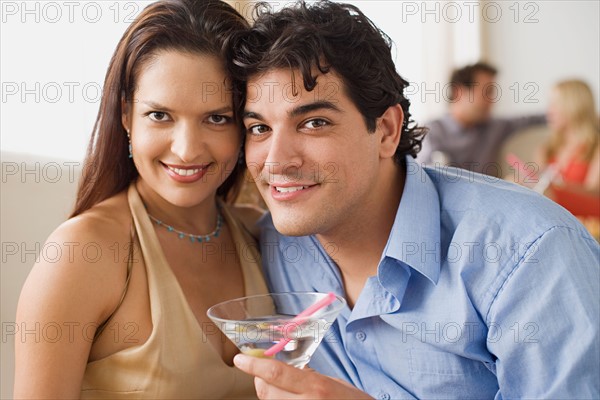 Portrait of couple at party, people in background. Photo : Rob Lewine