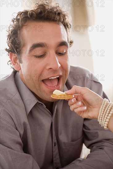 Woman's hand holding food in front of man's face. Photo : Rob Lewine