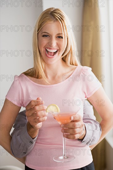 Man behind laughing woman holding cocktail. Photo : Rob Lewine