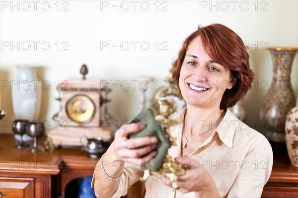 Smiling woman holding old candlestick . Photo :  Elena Elisseeva