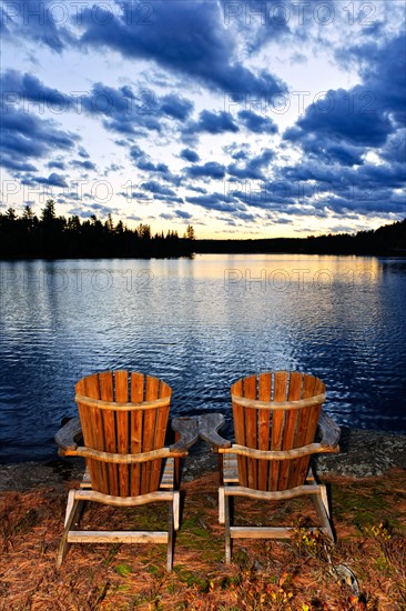 Canada, Ontario, Algonquin Park, Adirondack chairs on edge of lake. Photo :  Elena Elisseeva