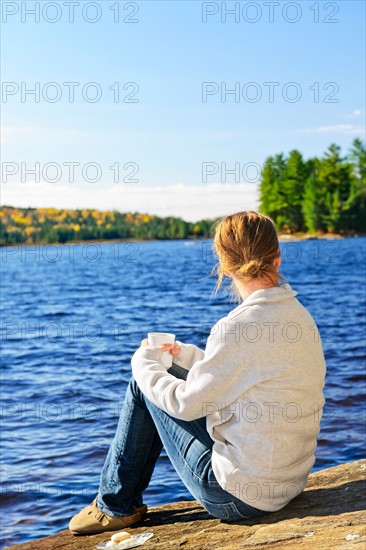 Canada, Ontario, Algonquin Park, Teenage girl sitting on rock and looking at lake. Photo : Elena Elisseeva