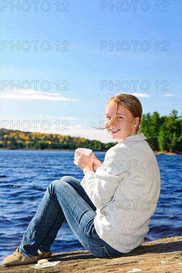 Canada, Ontario, Algonquin Park, Teenage girl sitting on rock and looking at camera. Photo :  Elena Elisseeva