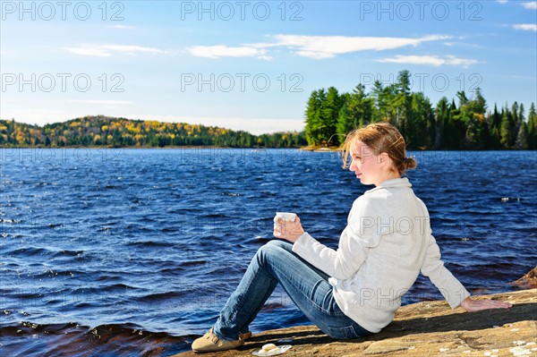 Canada, Ontario, Algonquin Park, Teenage girl sitting on rock and looking at lake. Photo :  Elena Elisseeva