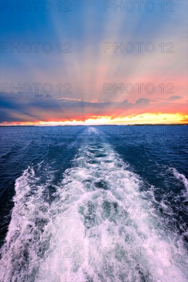 Waves behind boat, sunrise in background. Photo : Elena Elisseeva