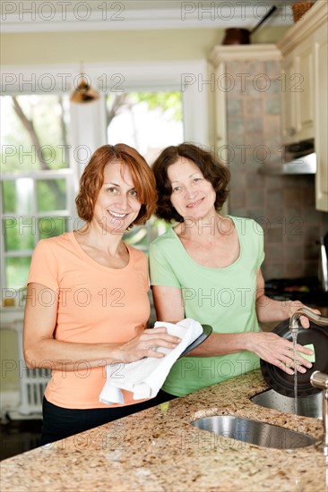 Mother and daughter doing dishes in kitchen. Photo : Elena Elisseeva