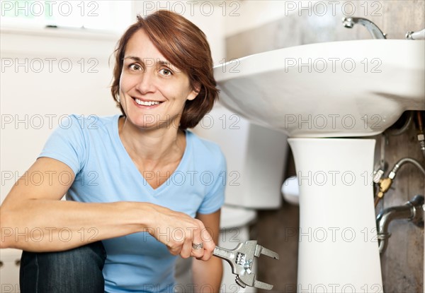 Woman plumbing in bathroom. Photo : Elena Elisseeva