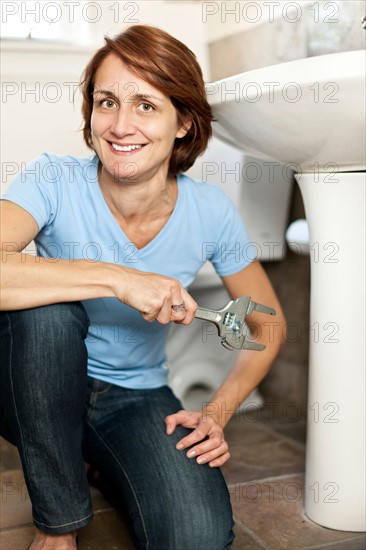 Woman plumbing in bathroom. Photo : Elena Elisseeva